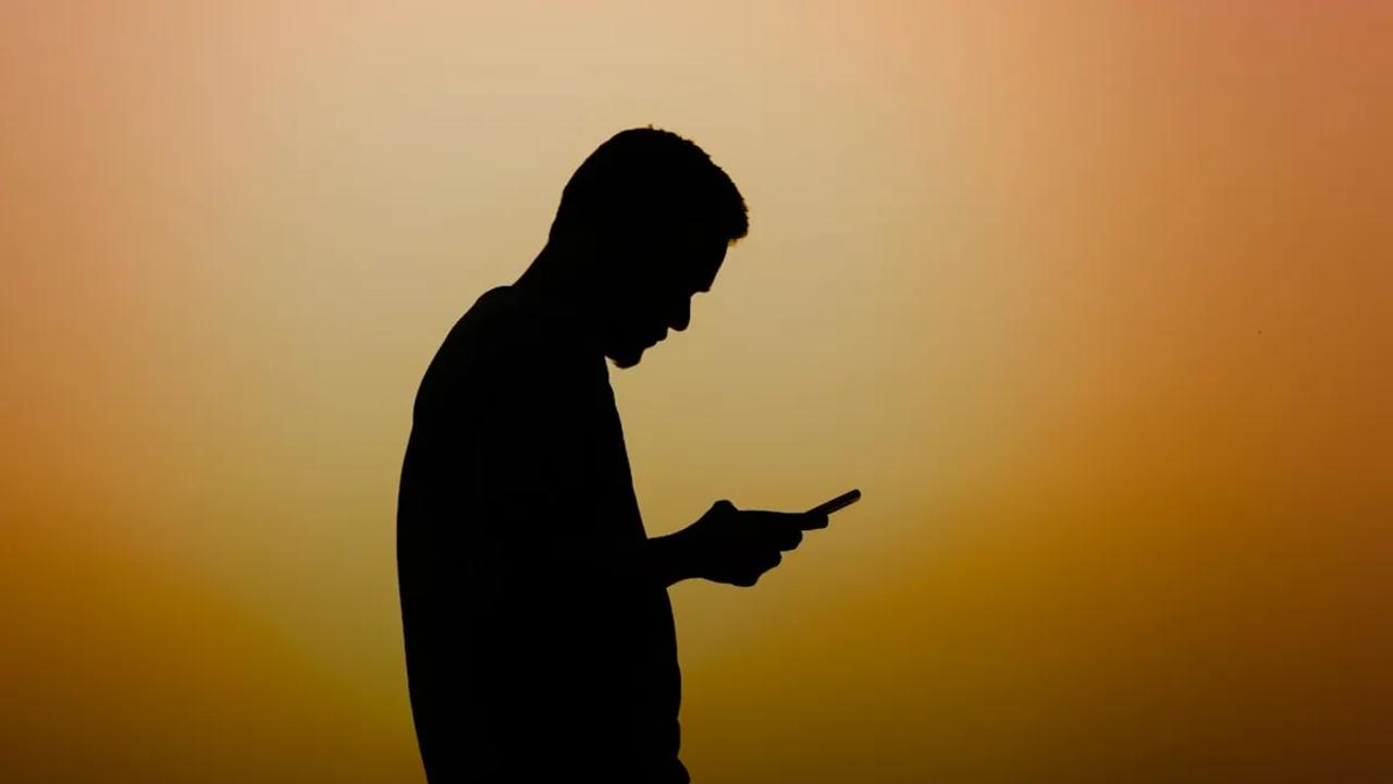 a silhouette of a man using a cell phone