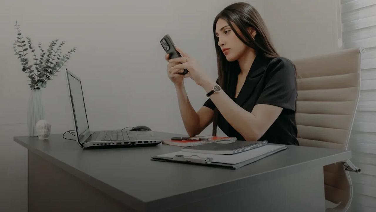 A woman using her phone at a desk