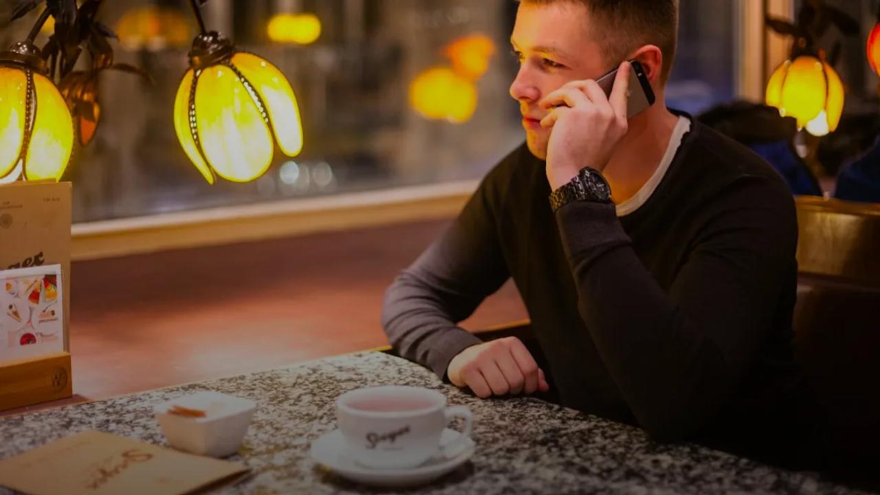 man sitting at the table while using smartphone