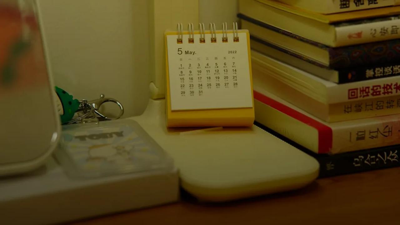 A small desk calendar sits beside a stack of books.