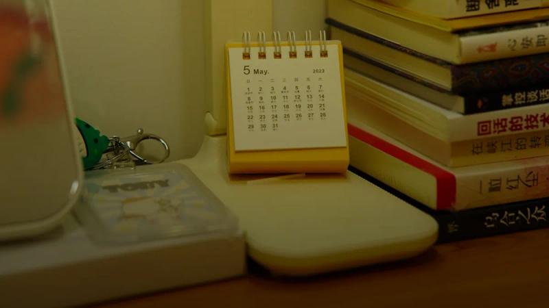 A small desk calendar sits beside a stack of books.