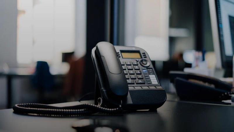 black ip desk phone on black wooden table