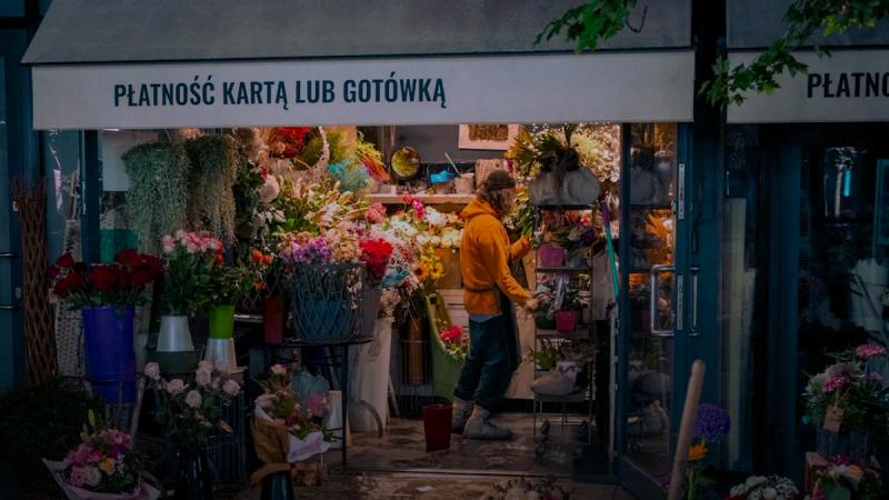 Man in yellow jacket inside a bustling flower shop
