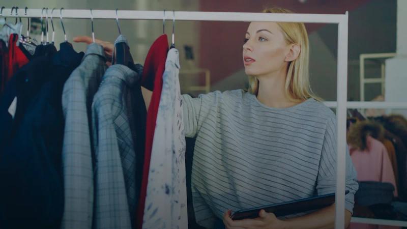 A woman chooses clothes from a rack.