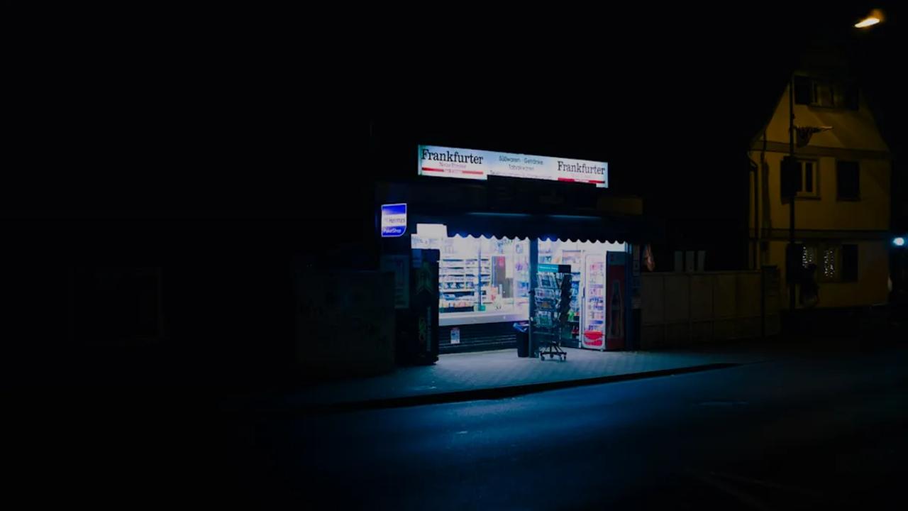 A brightly lit store at night on a dark street.