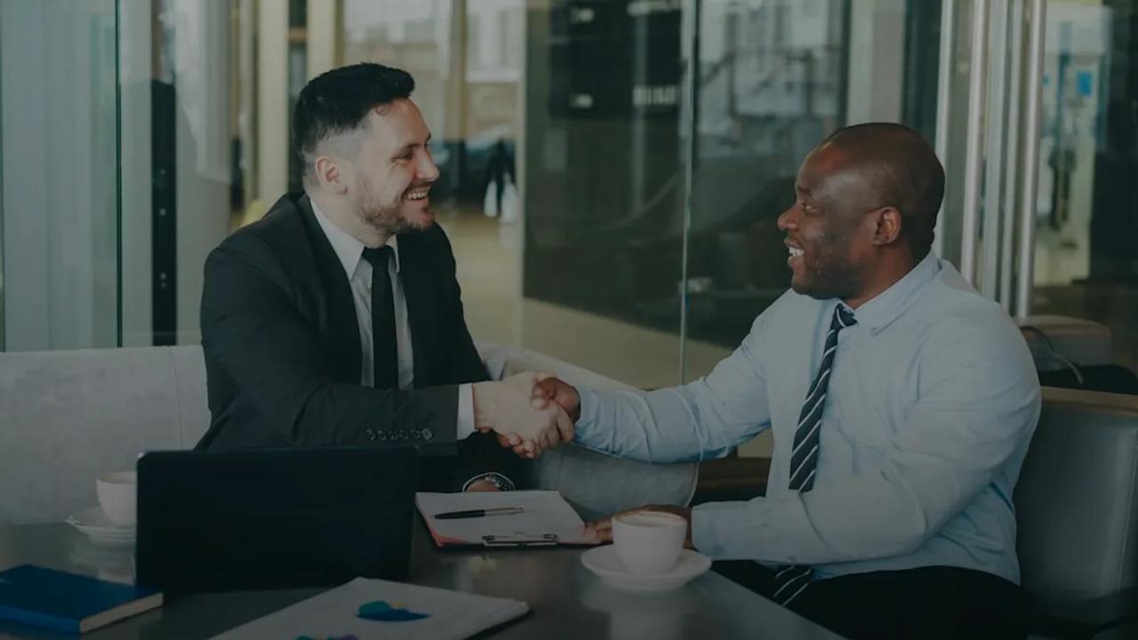 Two businessmen shaking hands across a table