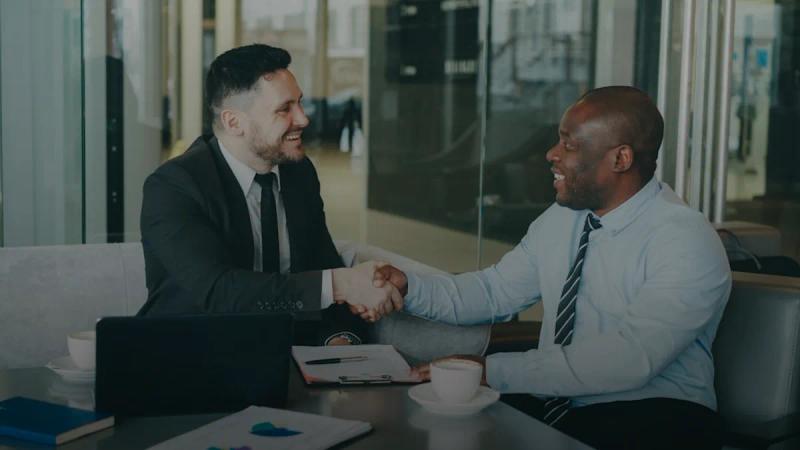 Two businessmen shaking hands across a table