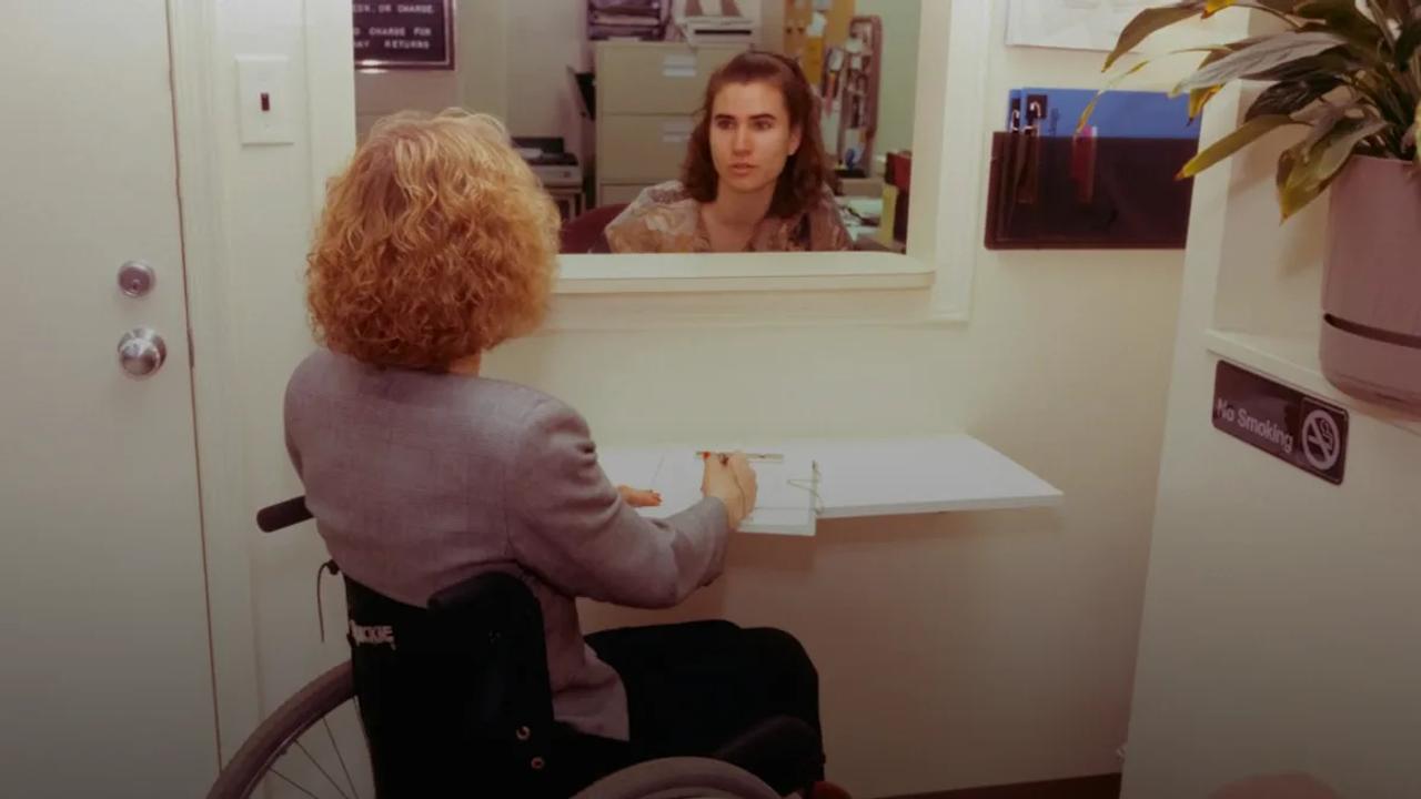 a woman sitting in a wheel chair in front of a mirror