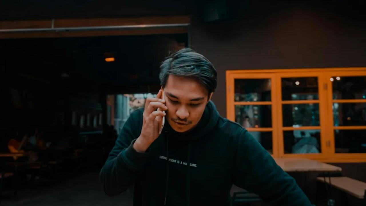 man using smartphone in black pullover hoodie