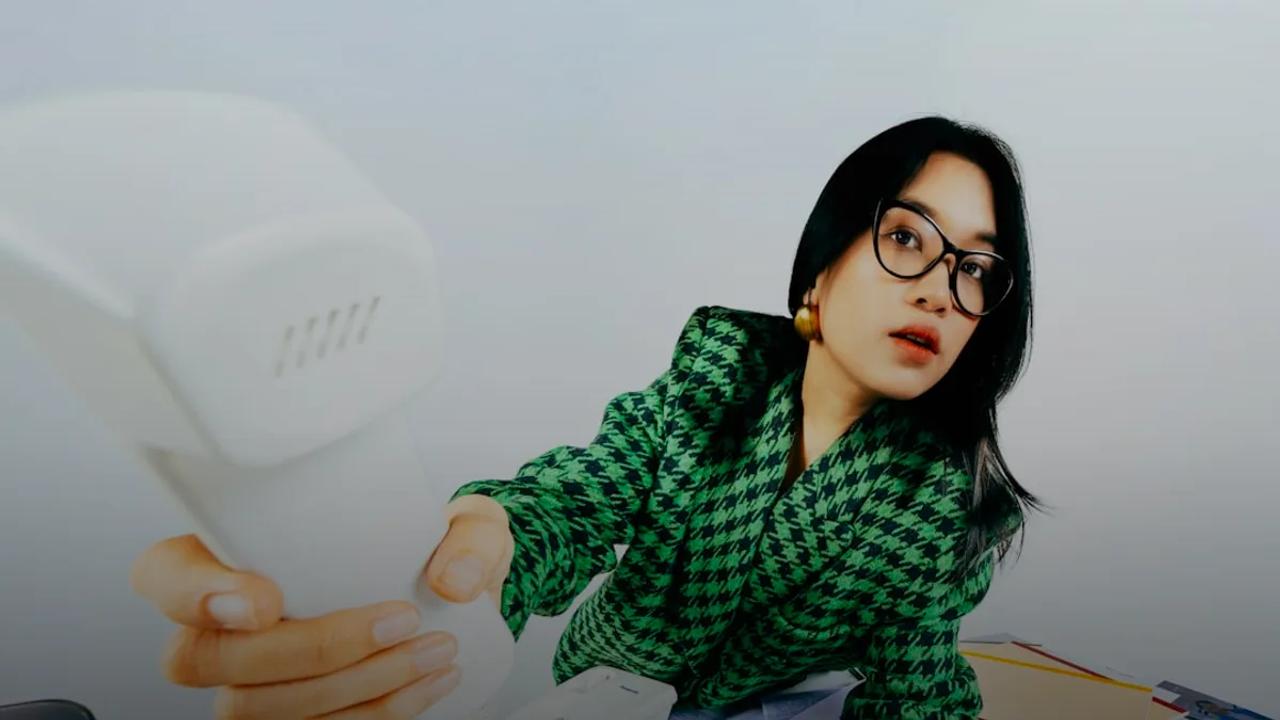 Woman in glasses reaching for a landline phone