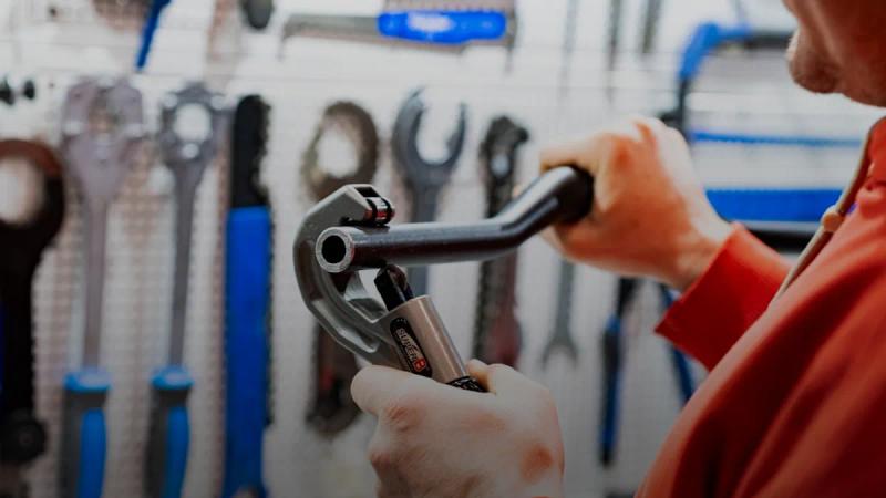 a man holding a wrench in front of a wall of tools