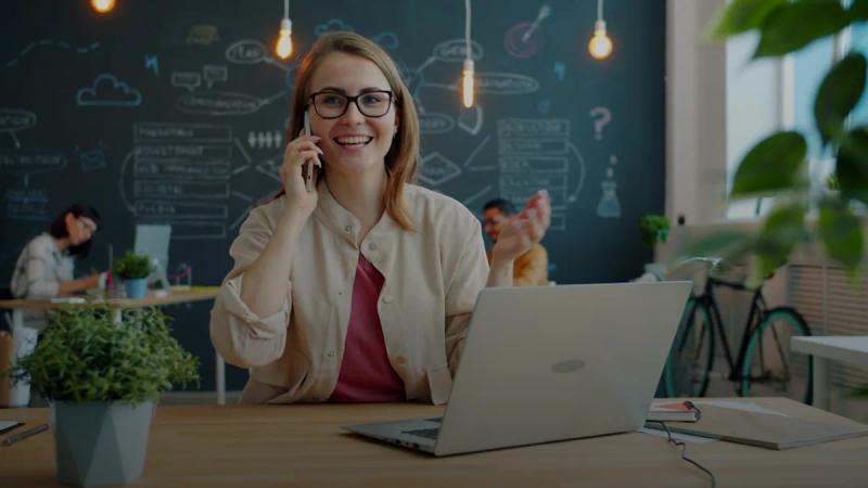 Smiling woman talking on phone in modern office