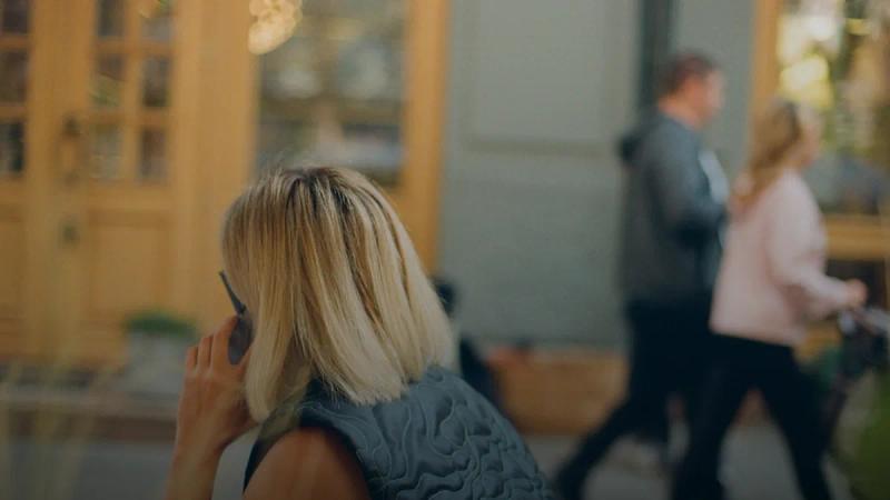 a woman sitting at a table talking on a cell phone