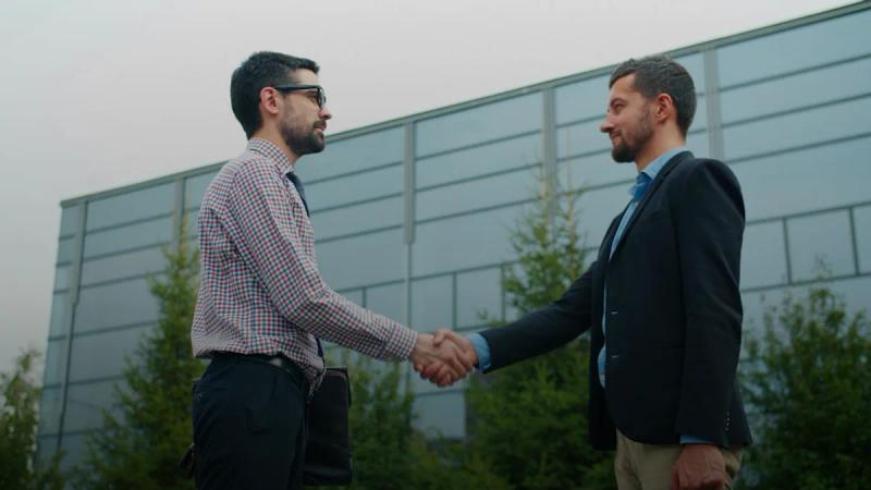 Two businessmen shaking hands outside modern building
