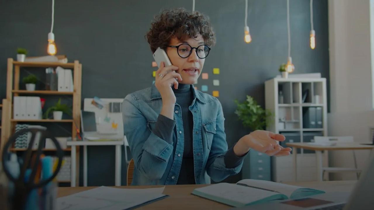 Woman talking on phone at desk in office