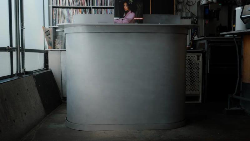 A woman stands behind a silver reception desk.