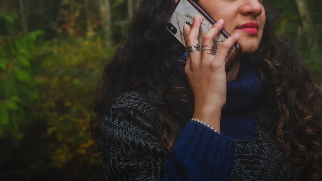 woman in blue sweater holding smartphone