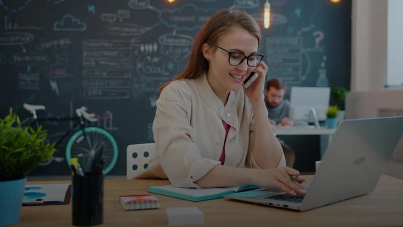 Woman talking on phone at desk with laptop
