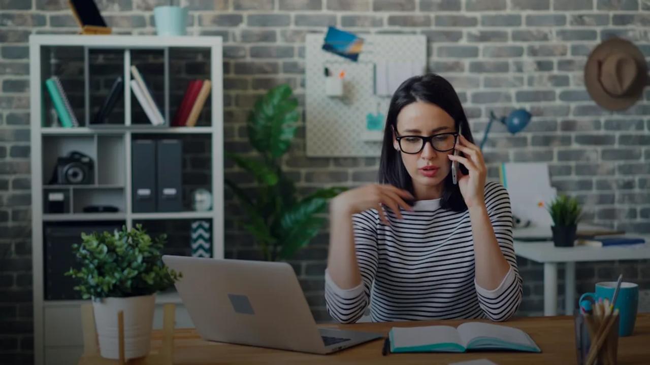 a woman sitting at a desk talking on a cell phone