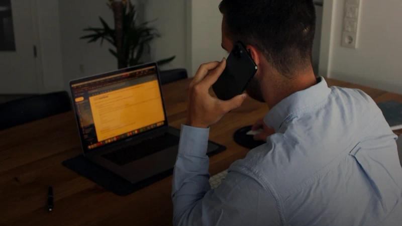 man in blue dress shirt holding black smartphone