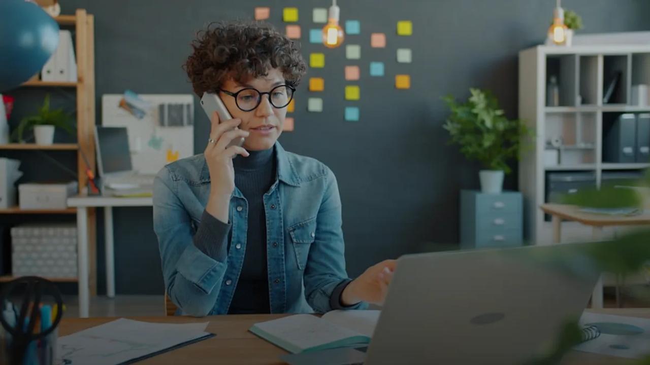 Woman talking on phone at desk with laptop