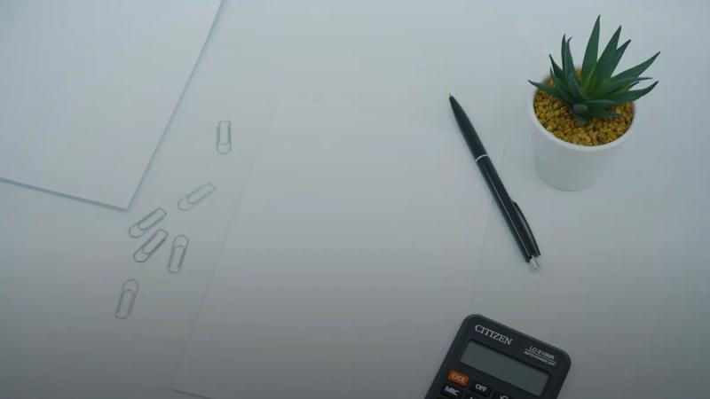 black calculator beside black pen on white printer paper