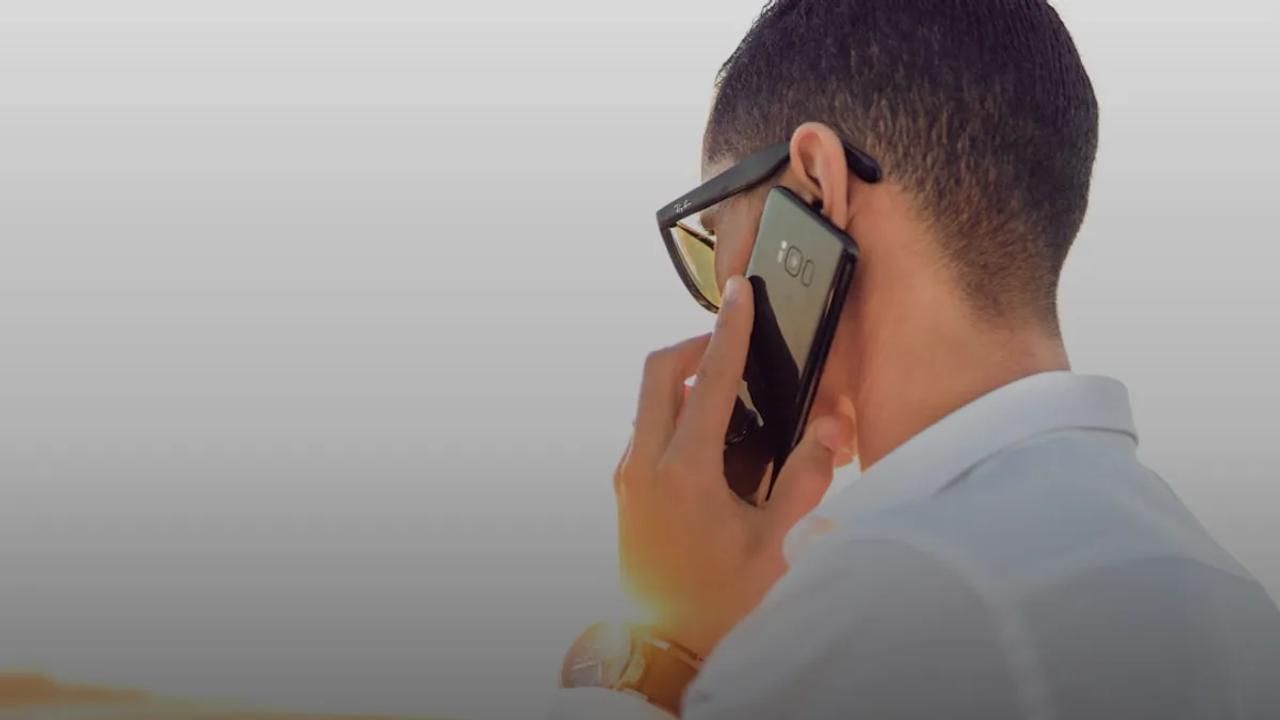 man holding smartphone standing in front of calm body of water