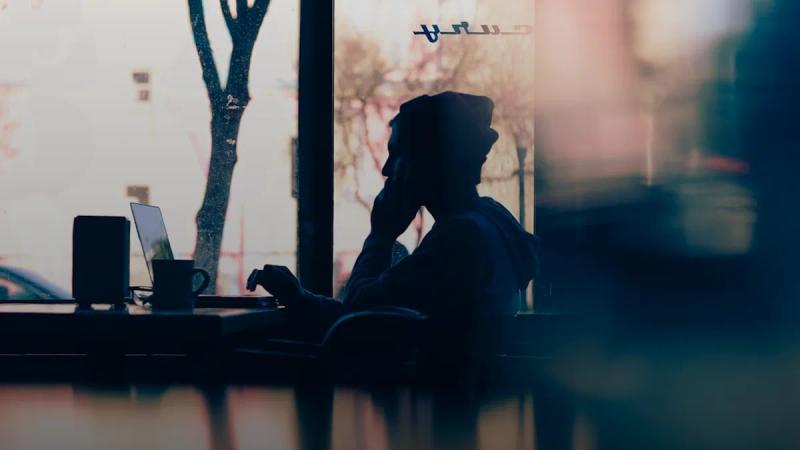 silhouette of a person sitting in front of a laptop