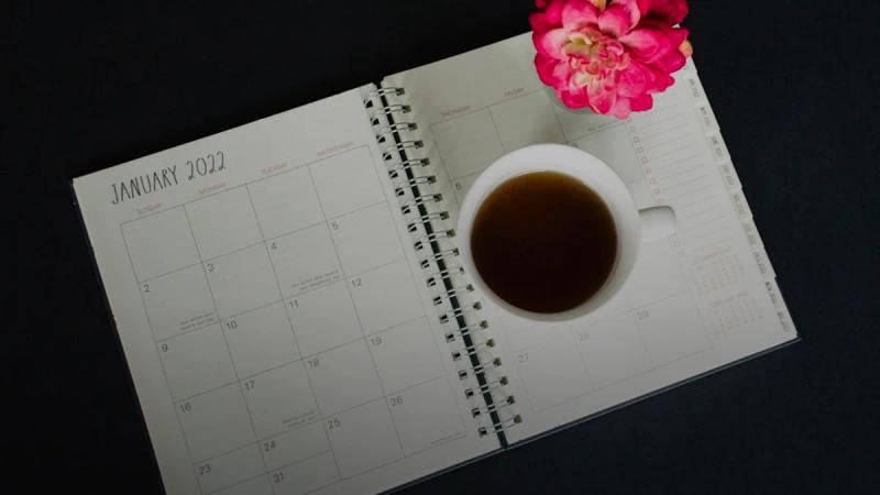 a cup of coffee sitting on top of a desk next to a calendar